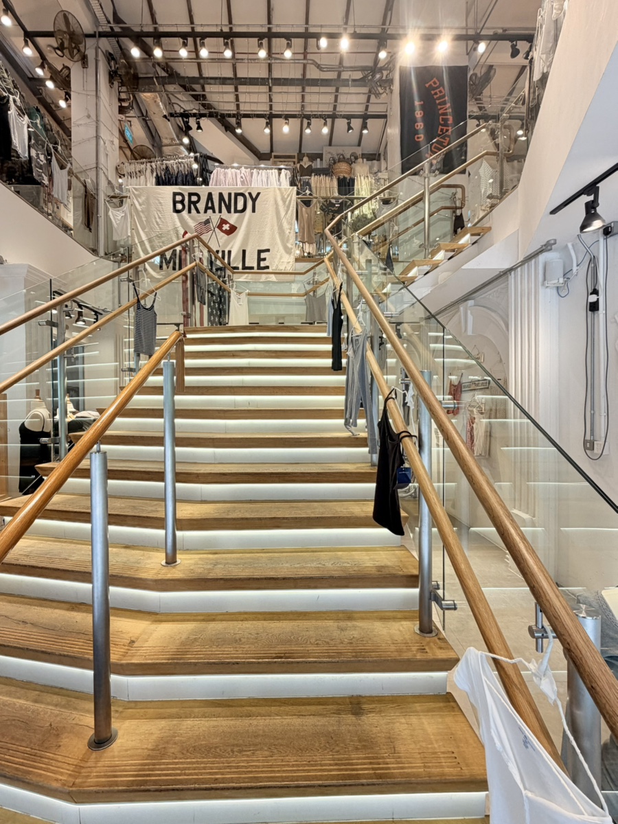 Wide wooden staircase leading up to a Brandy Melville banner